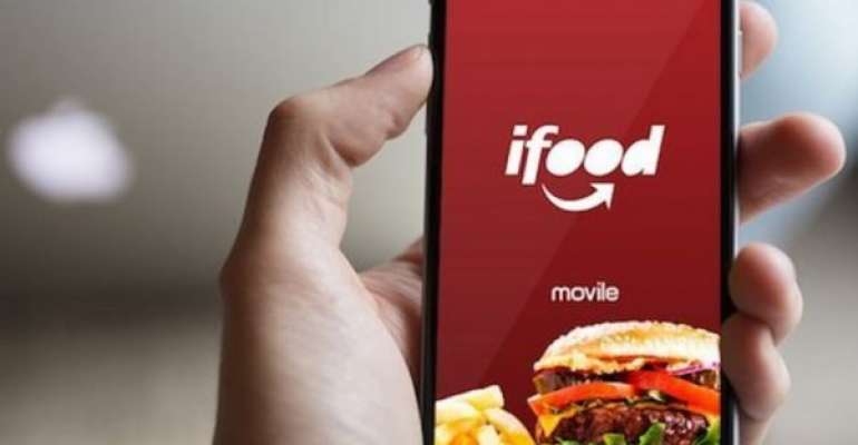 Mão segura celular com a logo do iFood em destaque