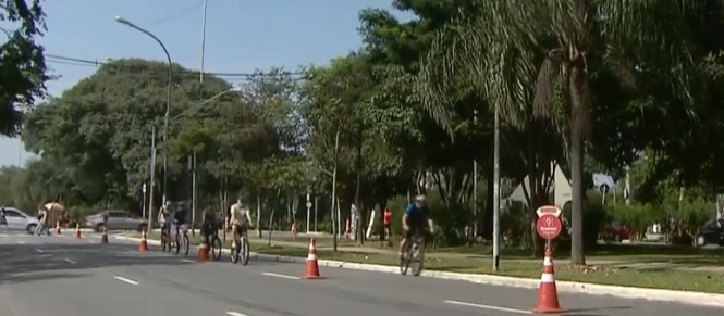 PEssoas andando em ciclofaixa protegida por cones