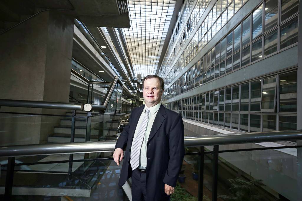 Cláudio Adolfo Martins Haase Homem branco de terno com deficiência visual na frente de uma empresa
