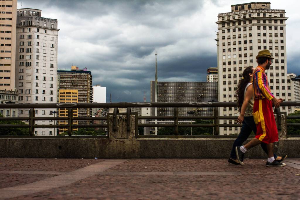 A imagem mostra duas pessoas caminhando em viaduto no centro de São Paulo