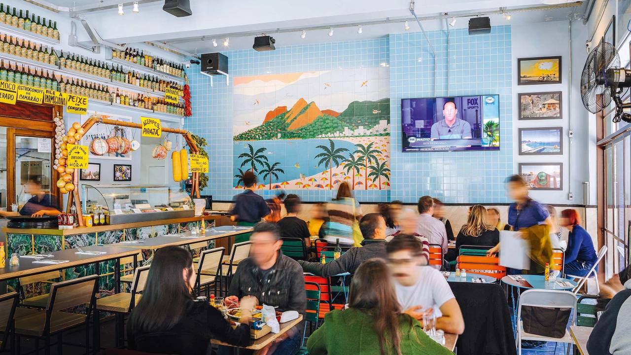 Ambient de bar com mesinhas e painel que lembra o Rio de Janeiro