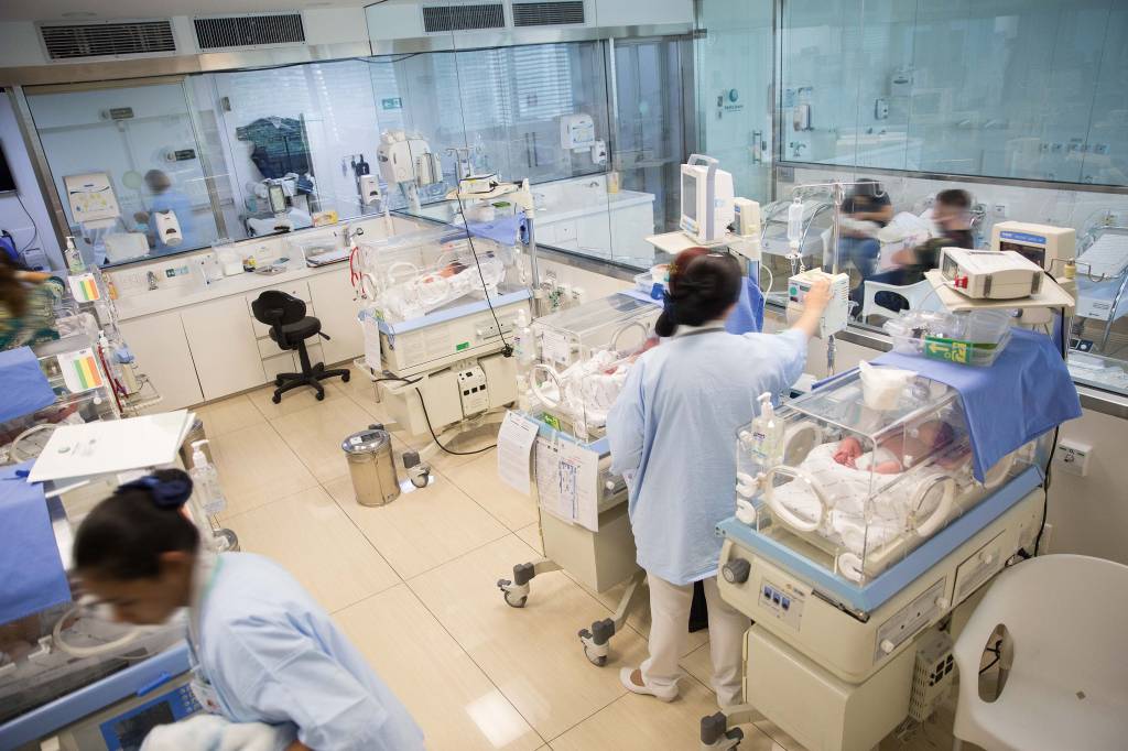 médicos em maternidade, junto com recém-nascidos