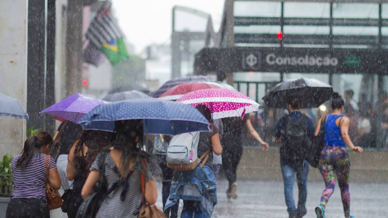 Imagem mostra pedestres caminhando na Avenida Paulista, próximo do metrô Consolação, embaixo de chuva