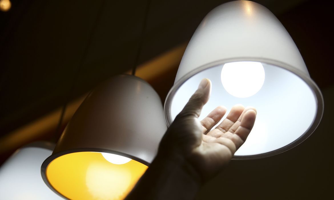 Imagem mostra a mão de uma pessoa trocando uma lâmpada