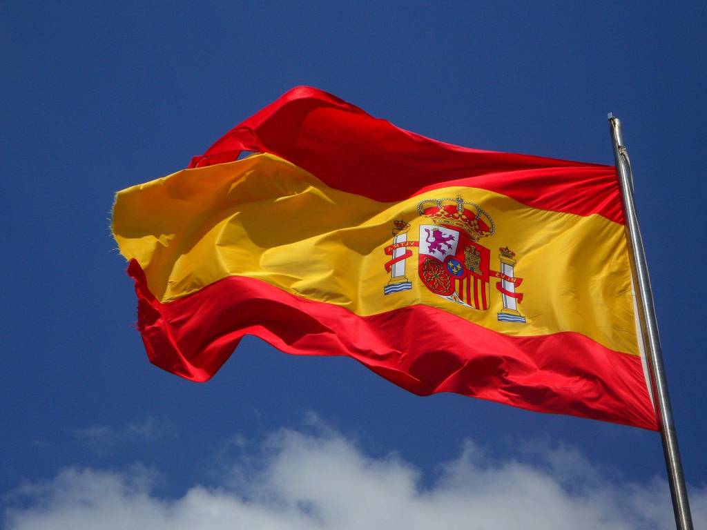 Imagem mostra bandeira da Espanha tremulando com céu ao fundo