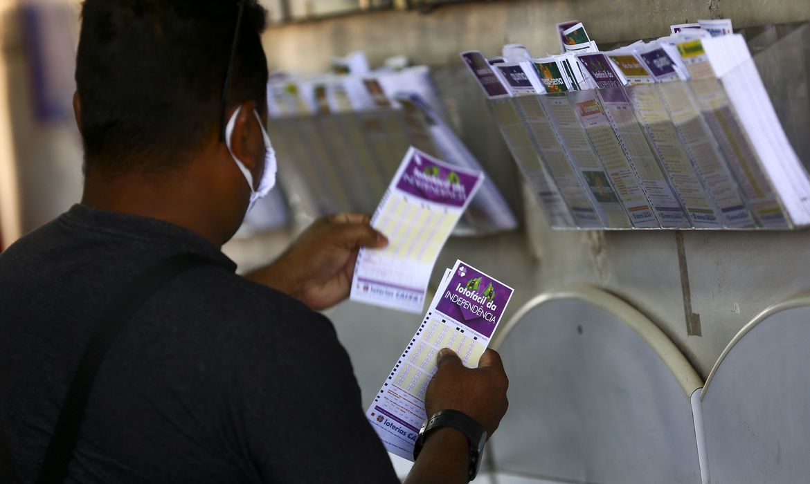 A foto mostra uma pessoa segurando bilhetes de loteria