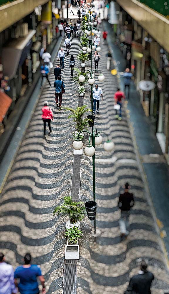 A imagem mostra o calçadão no Centro de São Paulo visto do alto com pessoas andando