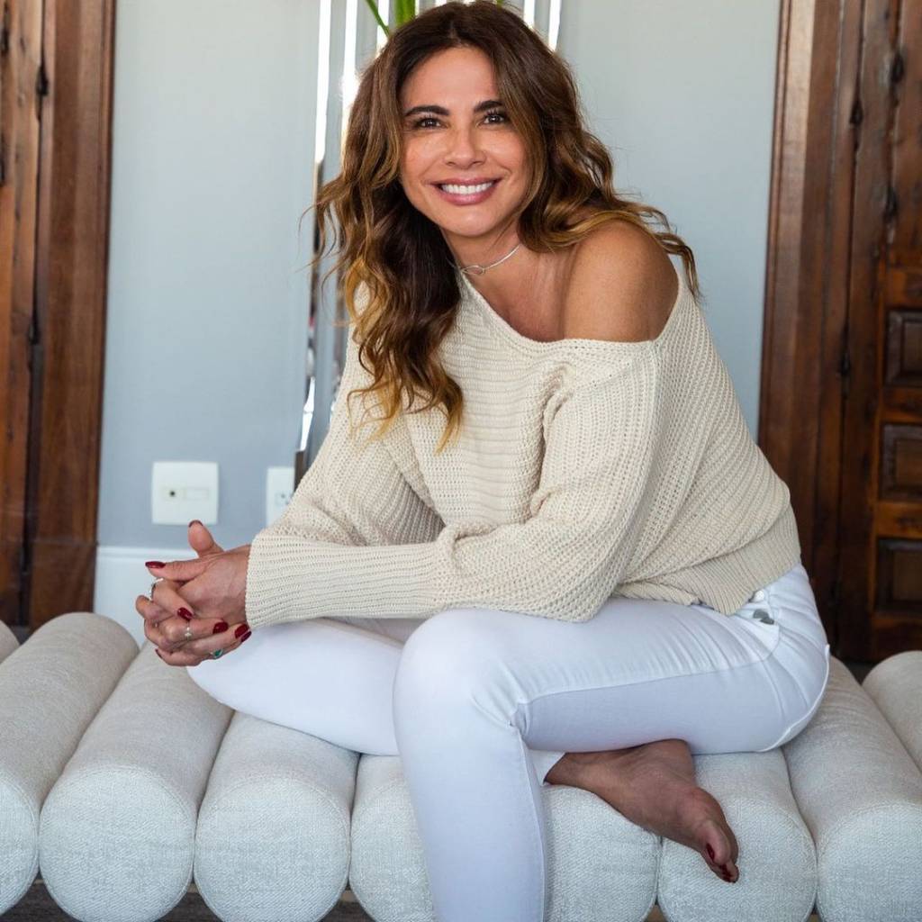 Luciana Gimenez sentada em um sofá branco, sorrindo