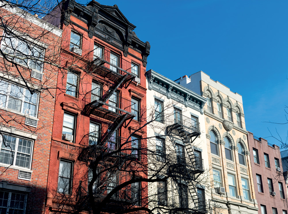 A row of colorful old brick buildings with fire escapes in the East Village of New York City