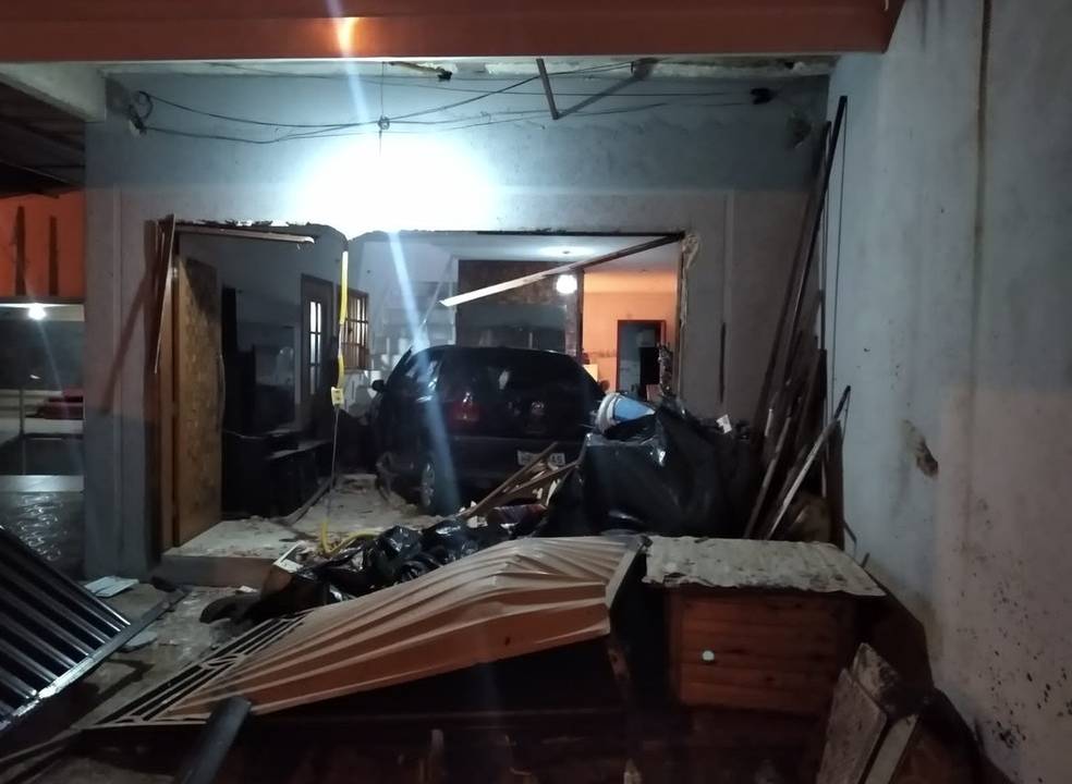 Carro dentro de uma sala. Portão e frente da casa totalmente destruídos