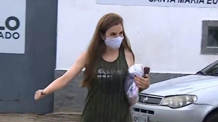 Suzane von Richtofen deixando a prisão, usando máscara e segurando seus pertences