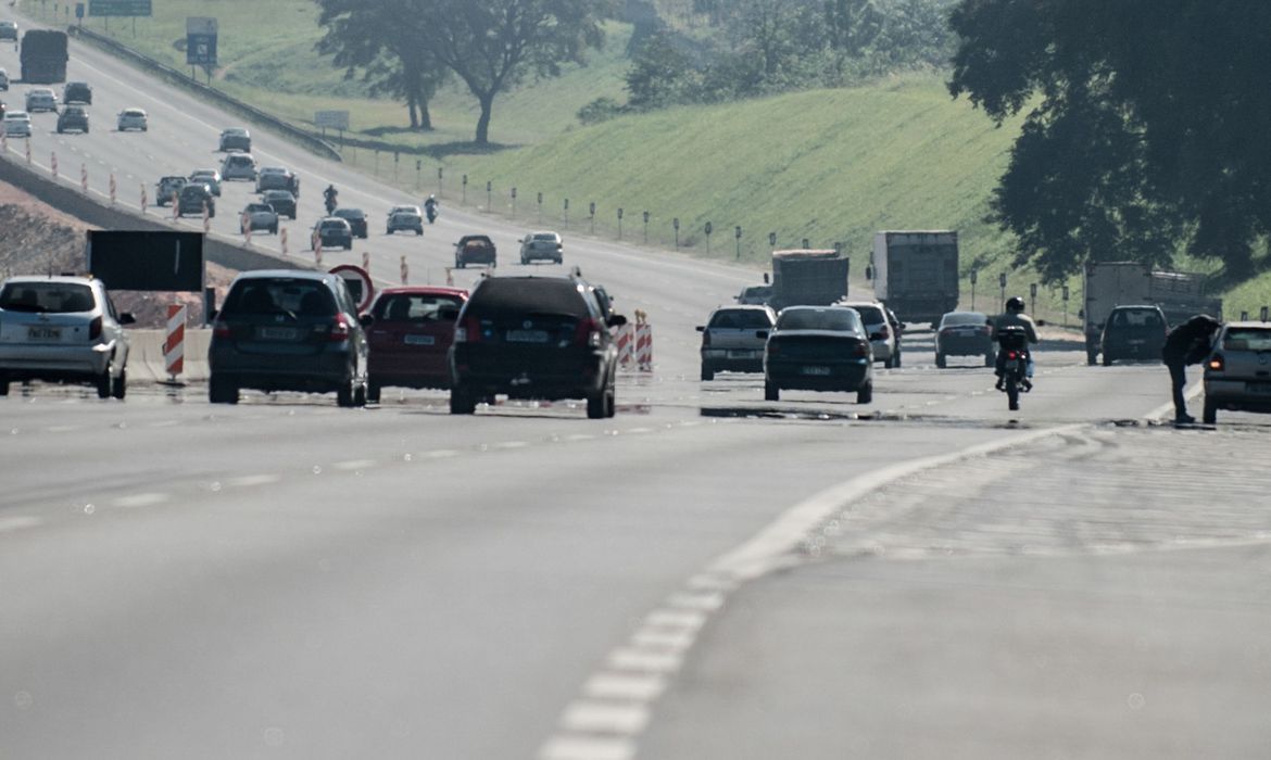 Imagem mostra movimento de carros em rodovia paulista. É possível ver uma longa pista de asfalto, com um gramado a lateral, típico das rodovias.