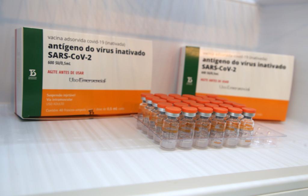 Imagem mostra frascos da CoronaVac, com embalagens da vacina ao fundo