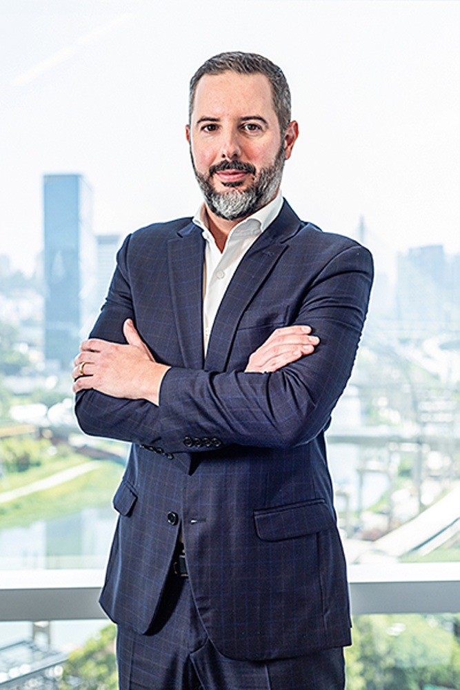 Thiago Castro, diretor executivo da Tegra, posa de braços cruzados e terno cinza-escuro.