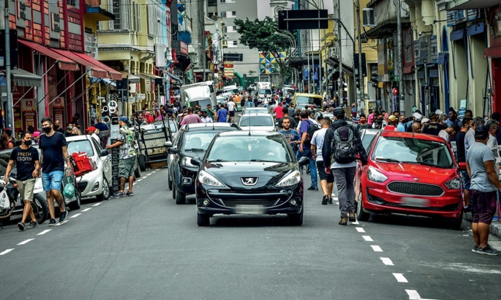 A imagem apresenta a rua Santa Efigênia congestionada de carros e com muitas pessoas nas calçadas