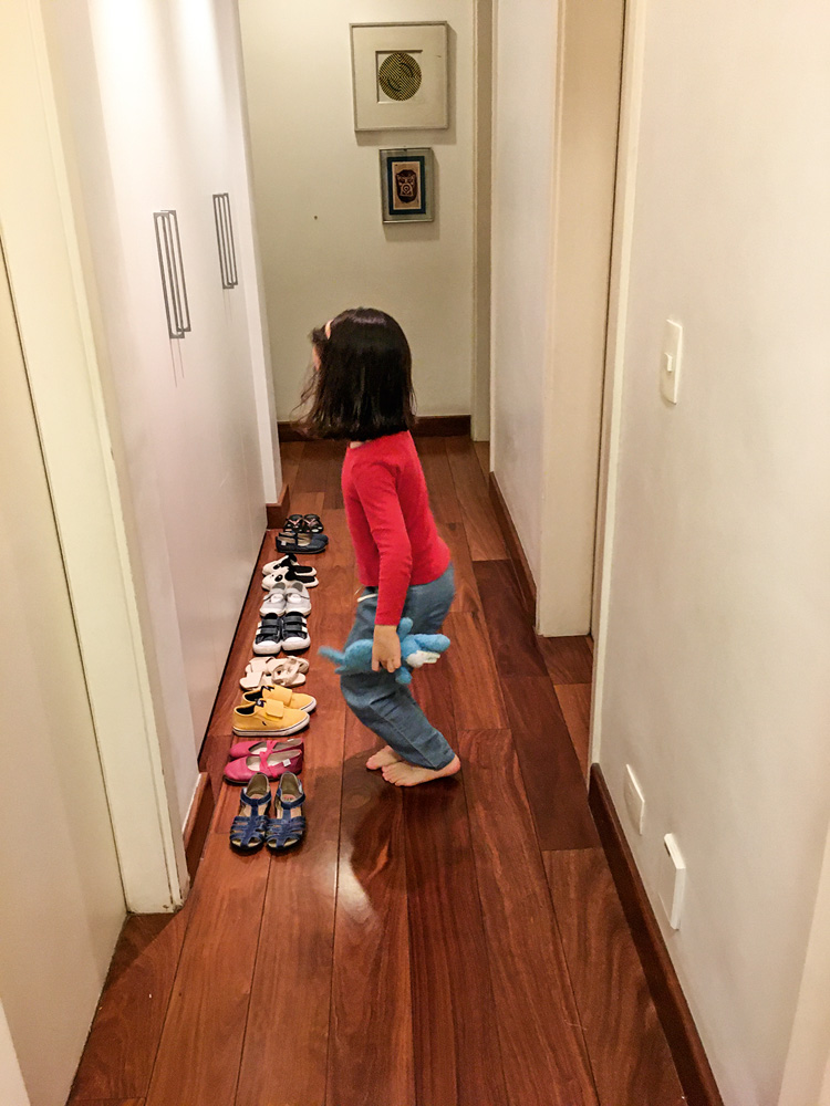 Um corredor com uma criança em frente a uma fila de sapatos