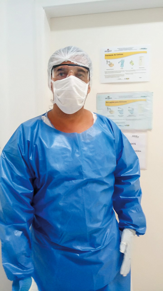 foto 1.jpg Clodoaldo veste touca, óculos de proteção, máscara e avental médico azul