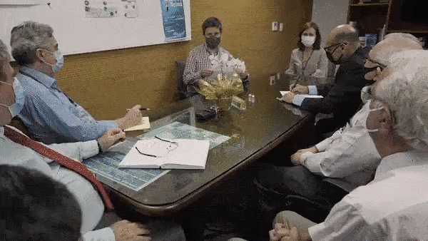 Cientistas do Instituto, sentados em uma mesa, Butantan aplaudem