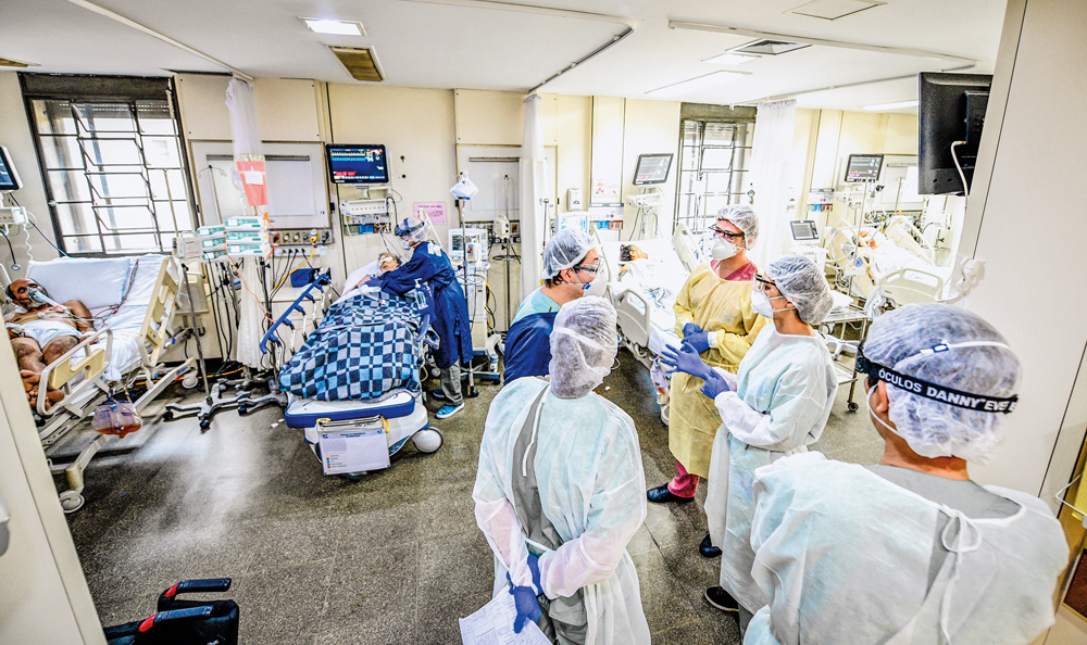 Imagem mostra UTI do Hospital das Clínicas, onde um paciente está deitado na maca e um grupo de profissionais da saúde trocam informações