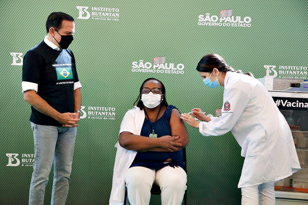 A enfermeira Mônica Calazans tomando a primeira dose da vacina CoronaVac, ao lado de João Dória, governador de São Paulo