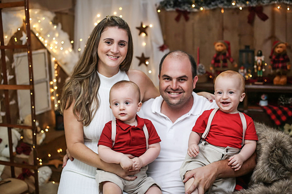 Roberta com o marido e os dois filhos, todos sentados e rindo em um sofá