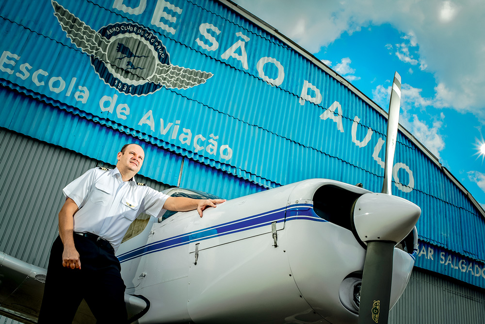 Fernando apoiado em um avião, à frente do Aeroclube