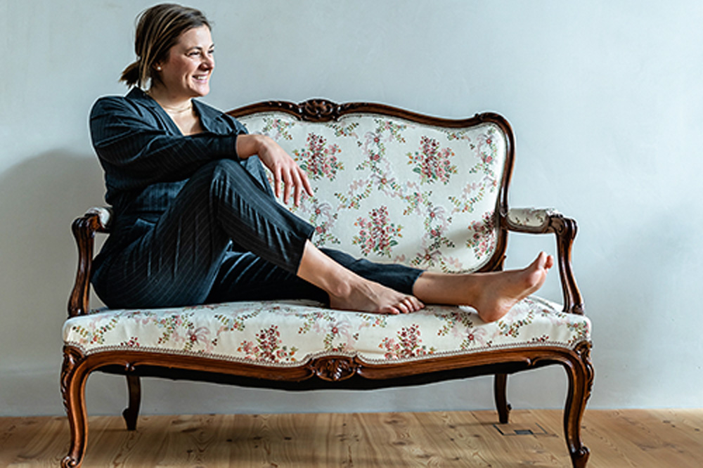 Artista Kalina Juzwiak posa para foto sentada em um sofá