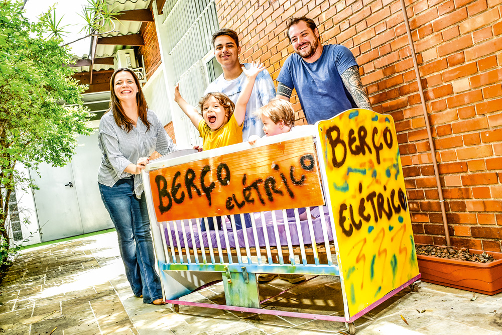 Família de Julia e Diogo com o famoso carrinho de bebê escrito "Berço Elétrico"