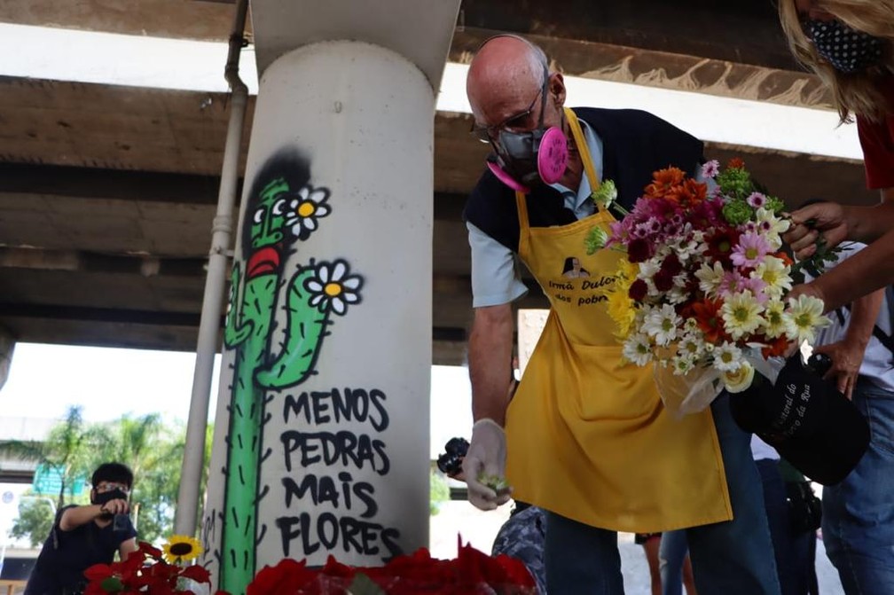 Padre Júlio Lancelotti deposita flores em viaduto.