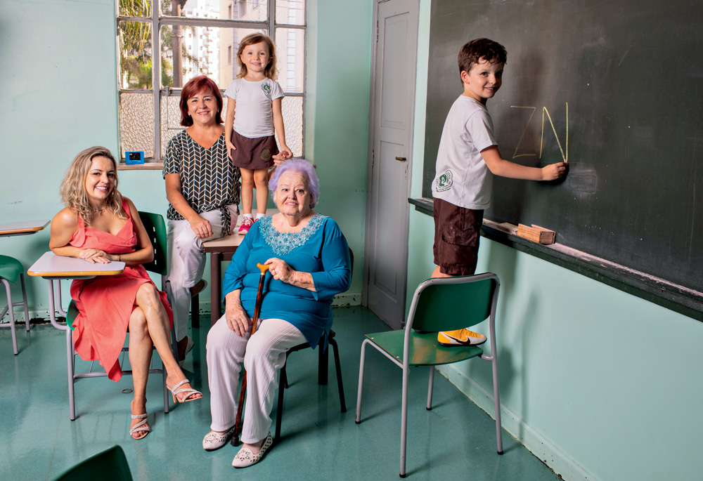 Família em uma sala de aula, com um menino rabiscando a lousa