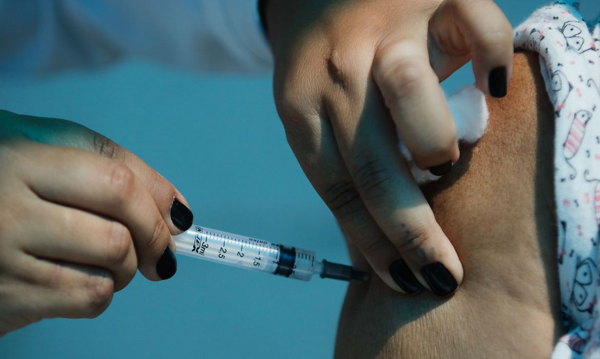 Imagem de uma profissional da saúde aplicando a vacina no braço de uma pessoa
