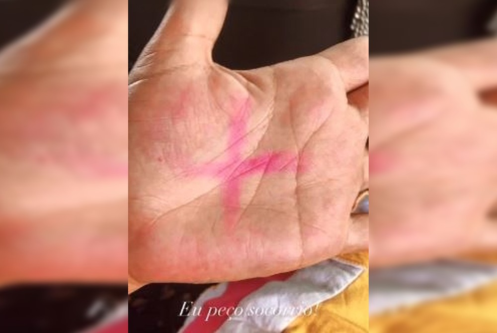 x escrito em rosa na mão de mulher