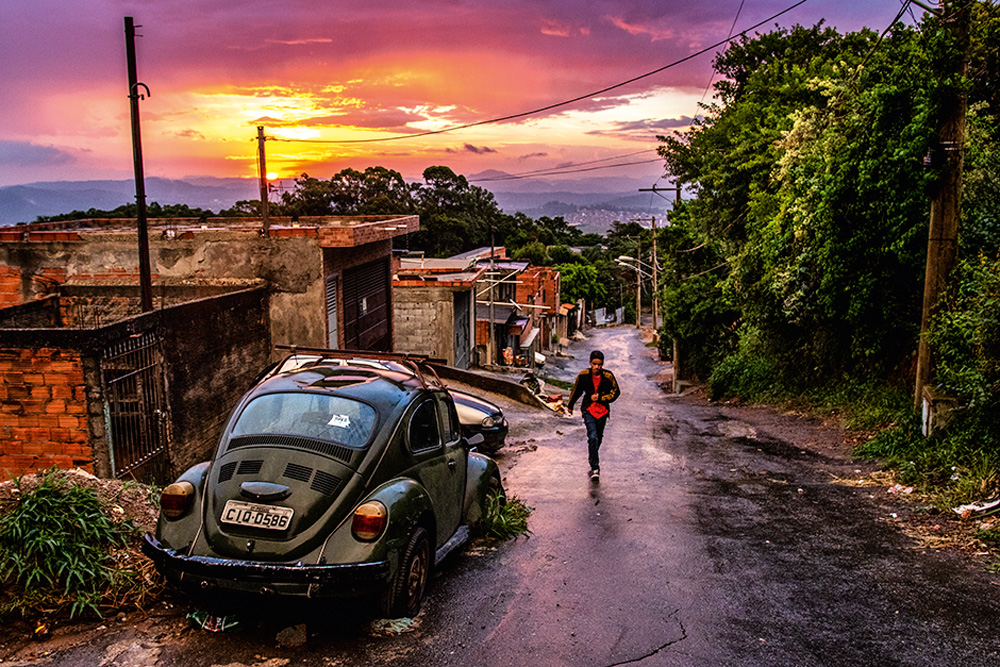 Ladeira da ZN, uma pessoa desce a rua com uma mochila durante o pôr do sol