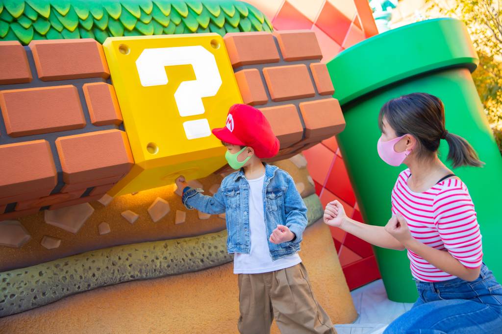 Criança de máscara batendo no bloco do Mario World