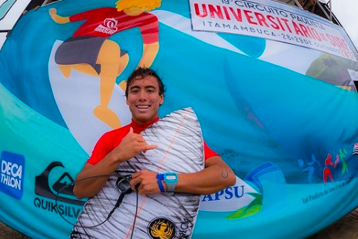 Imagem mostra Pedro Tanaka segurando prancha durante torneio de surfe universitário