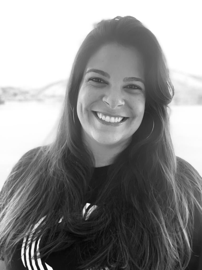 Carolina Badaró, COO da startup de mobilidade urbana Quicko, sorri em foto preto e branco.