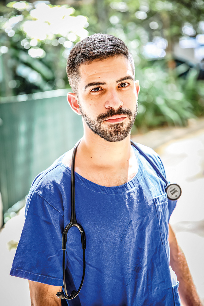 Matheus Gonçalves, com uma roupa azul e um estetoscópio no ombro