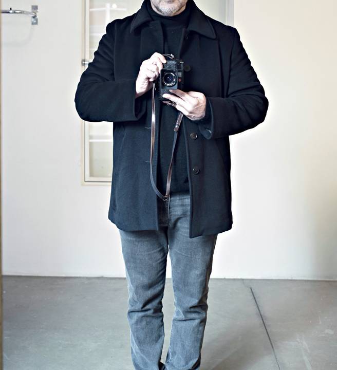 O fotógrafo Bob Wolfenson tirando uma fotografia de si mesmo no espelho. A imagem é um reflexo dele mesmo.
