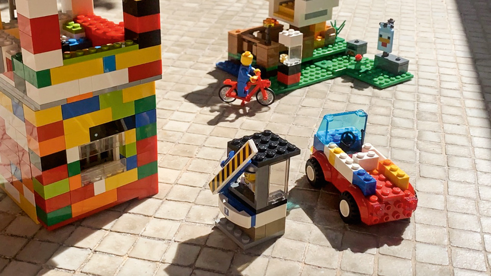 Brinquedos de lego no chão. Uma torre, carrinhos, bicicleta, cabine de porteiro