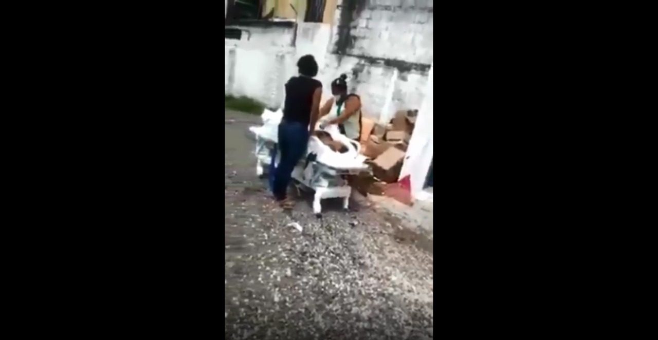 A imagem é um print do vídeo em que mostra familiares roubando o corpo do hospital, empurrando a maca pela rua