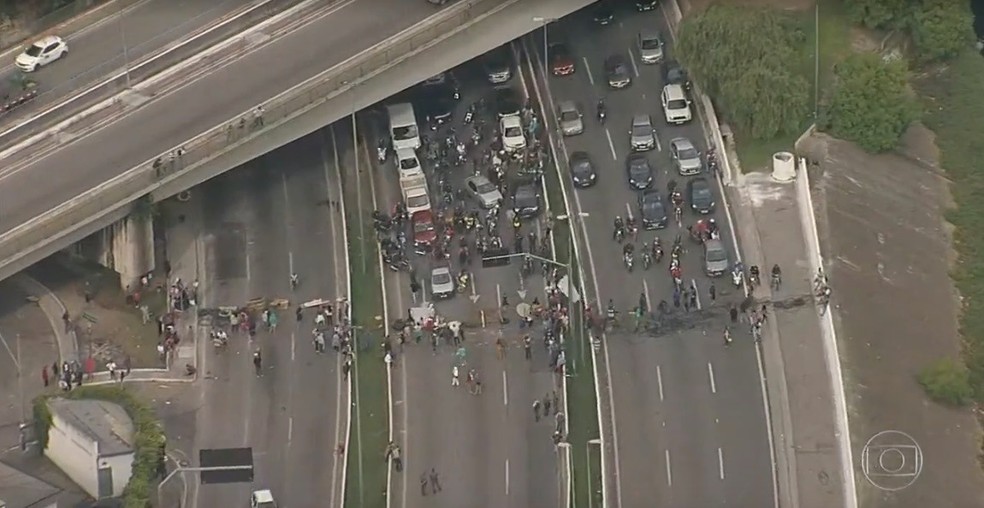A imagem mostra o bloqueio na Marginal Tietê por manifestantes; pessoas impedem veículos de passarem pela pista