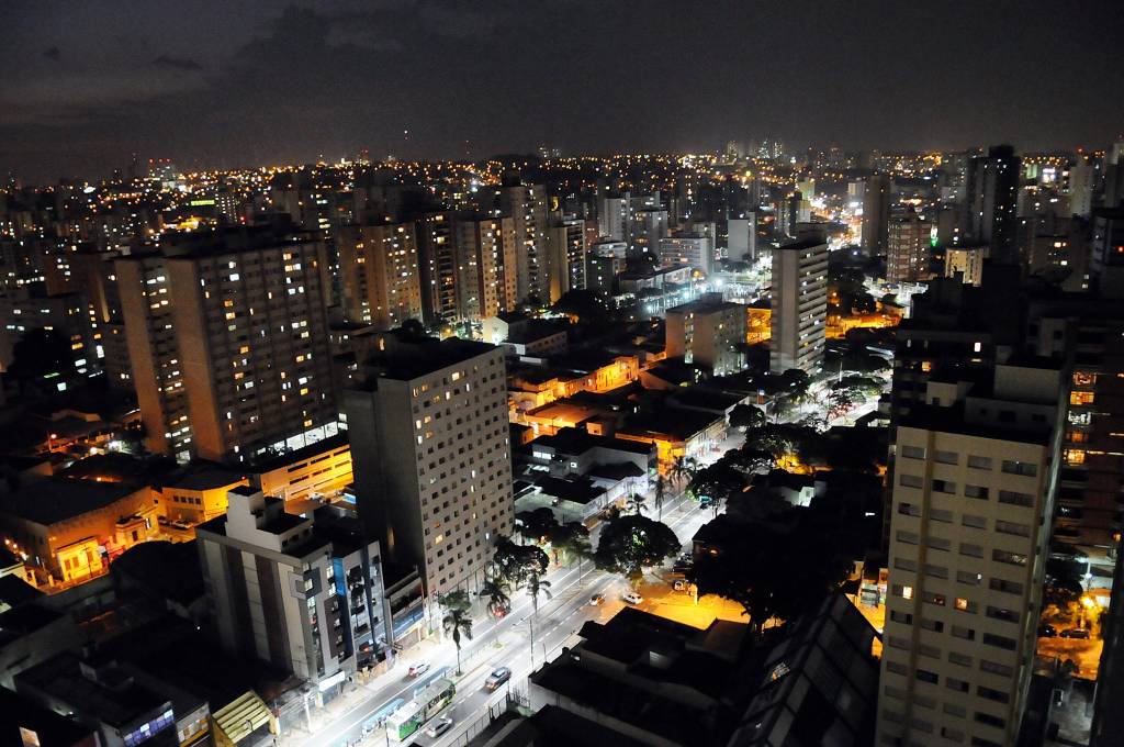 A imagem mostra a cidade de Campinas à noite, com prédios iluminados