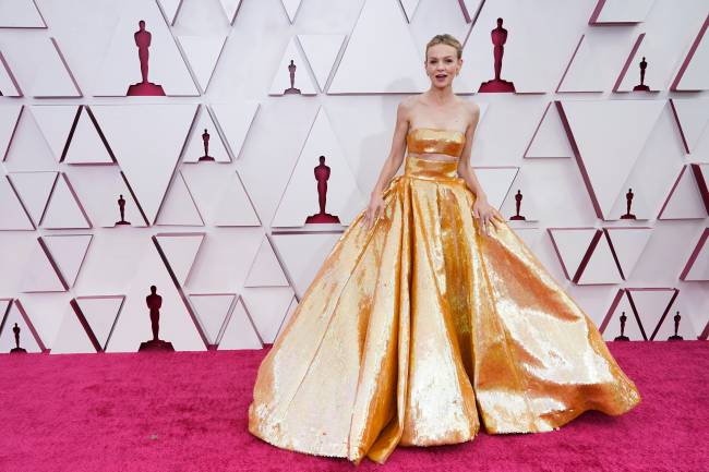 A atriz Carey Mulligan no tapete vermelho do Oscar com um vestido dourado