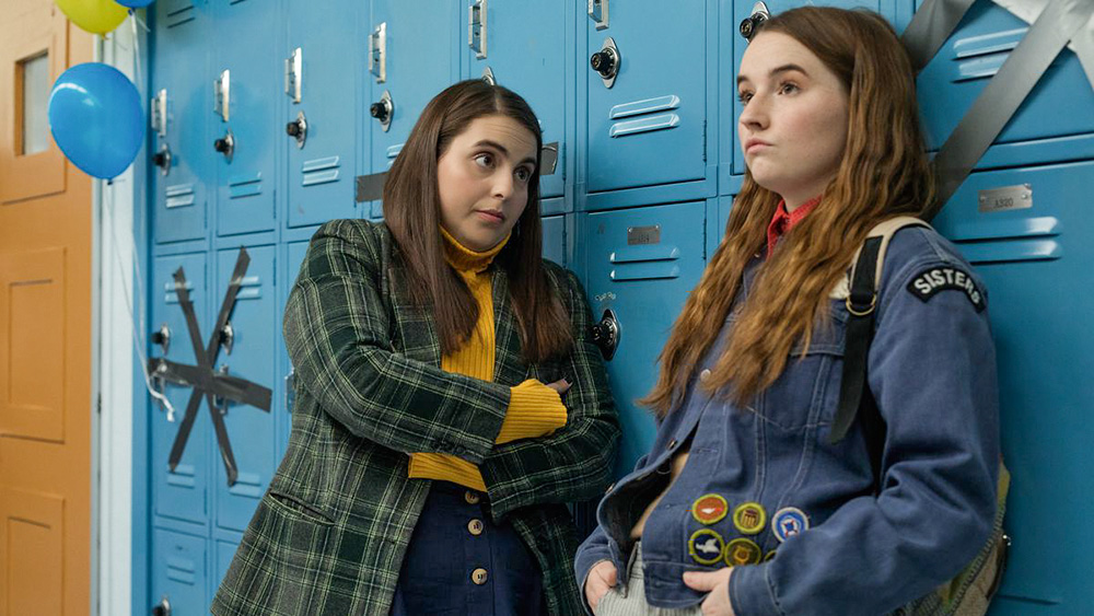 Duas meninas conversam apoiadas em armários escolares azuis