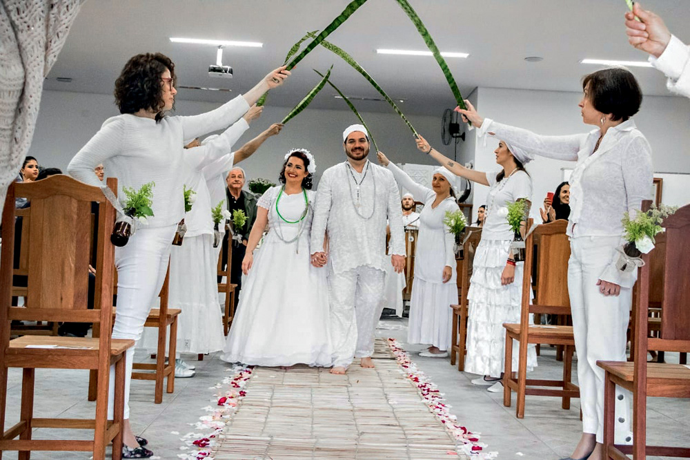 Daniel e Tatiana entram em sua cerimônia umbandista de casamento sendo recebidos pelos convidados segurando folhas de espada-de-são-jorge