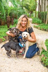 Luisa Mell, ativista e apresentadora de TV, posa de joelhos abraçada com três cachorros.