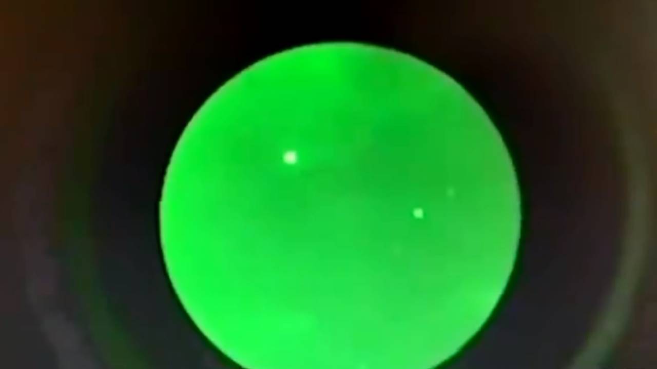 Imagem bastante esverdeada e difusa mostra filmagem de dois objetos triangulares bastantes distantes pairando sobre o céu