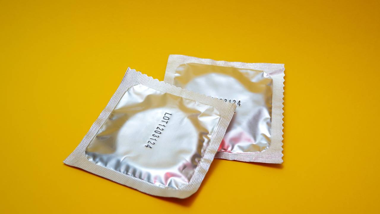 Imagem mostra duas embalagens de camisinha em um fundo amarelo