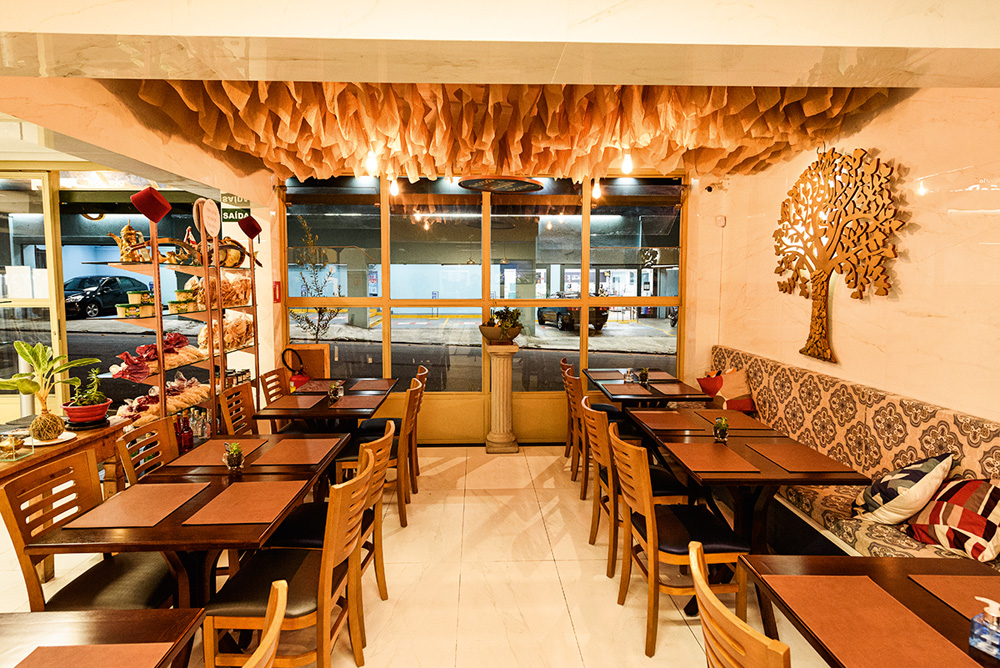 Salão pequeno do restaurante Shahiya com mesas espalhadas dos lados direito e esquerdo.