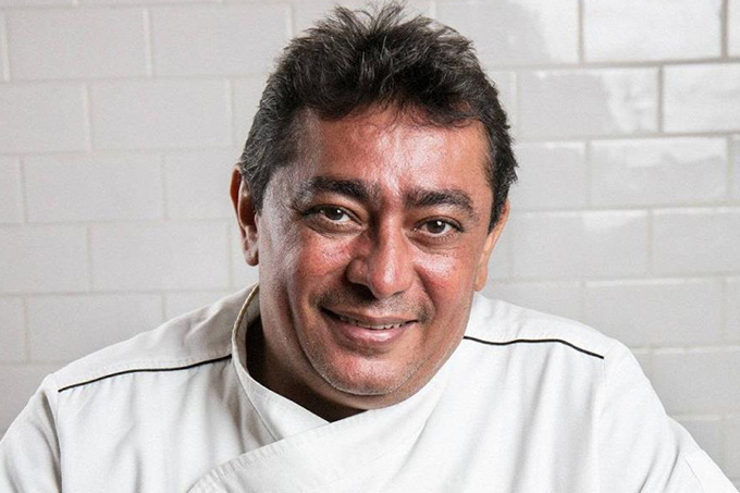 Bastista sorrindo, usando sua roupa de chef da cor branca.